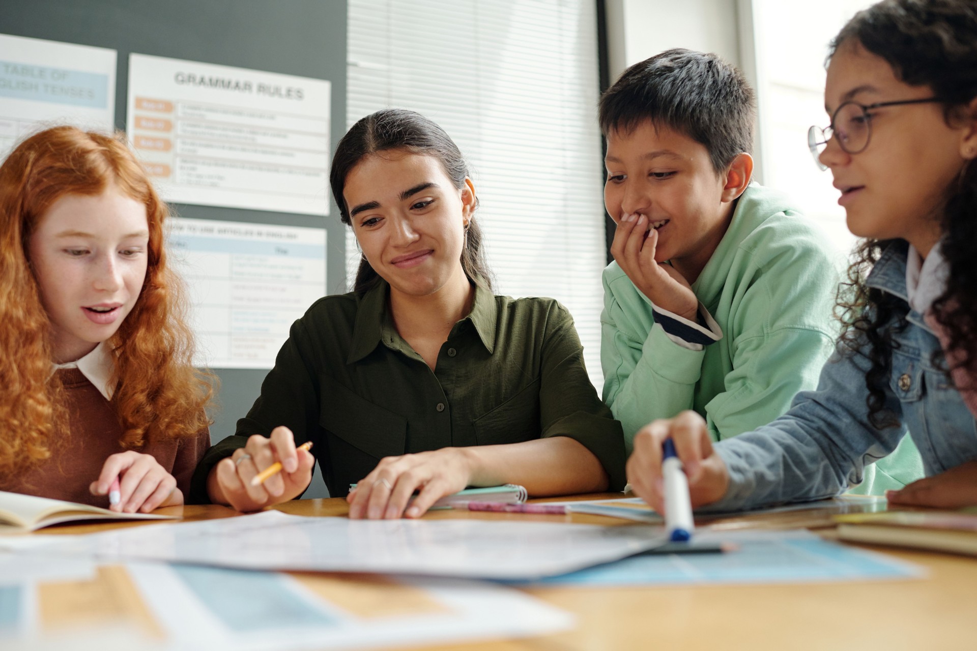 Group of clever schoolkids and their teacher discussing new grammar rules