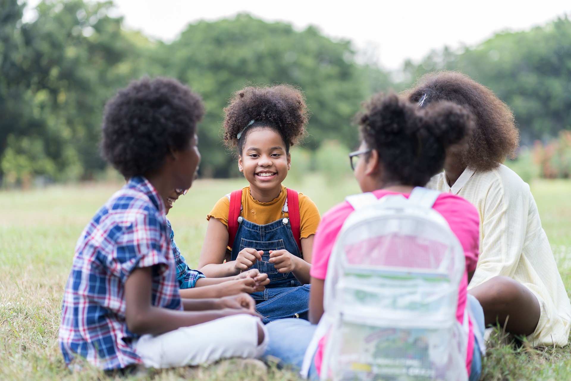 Group of African American children learning and writing book in the park. Boy and girl sitting and learning outside the classroom. Kids field trips outside. Kids and educational concept